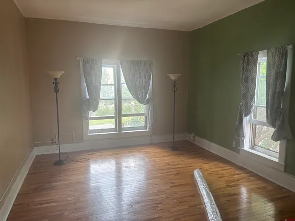 a view of an empty room with wooden floor and a window