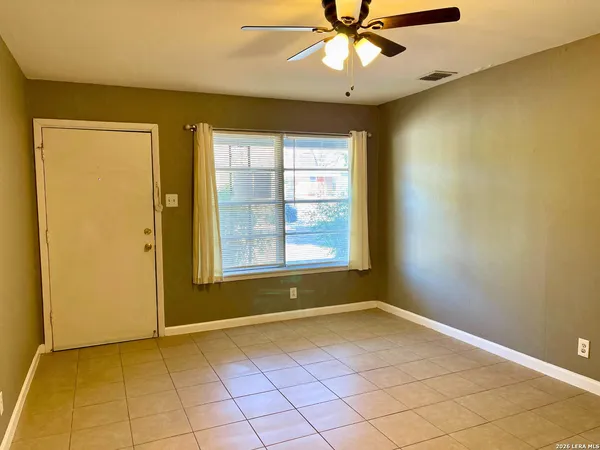 an empty room with a chandelier fan and windows