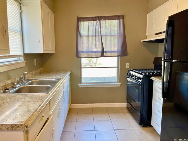 a kitchen that has a sink cabinets counter top space and stainless steel appliances