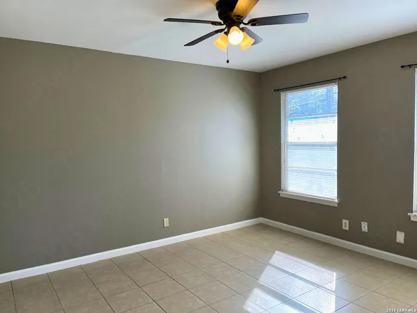 an empty room with window and chandelier fan