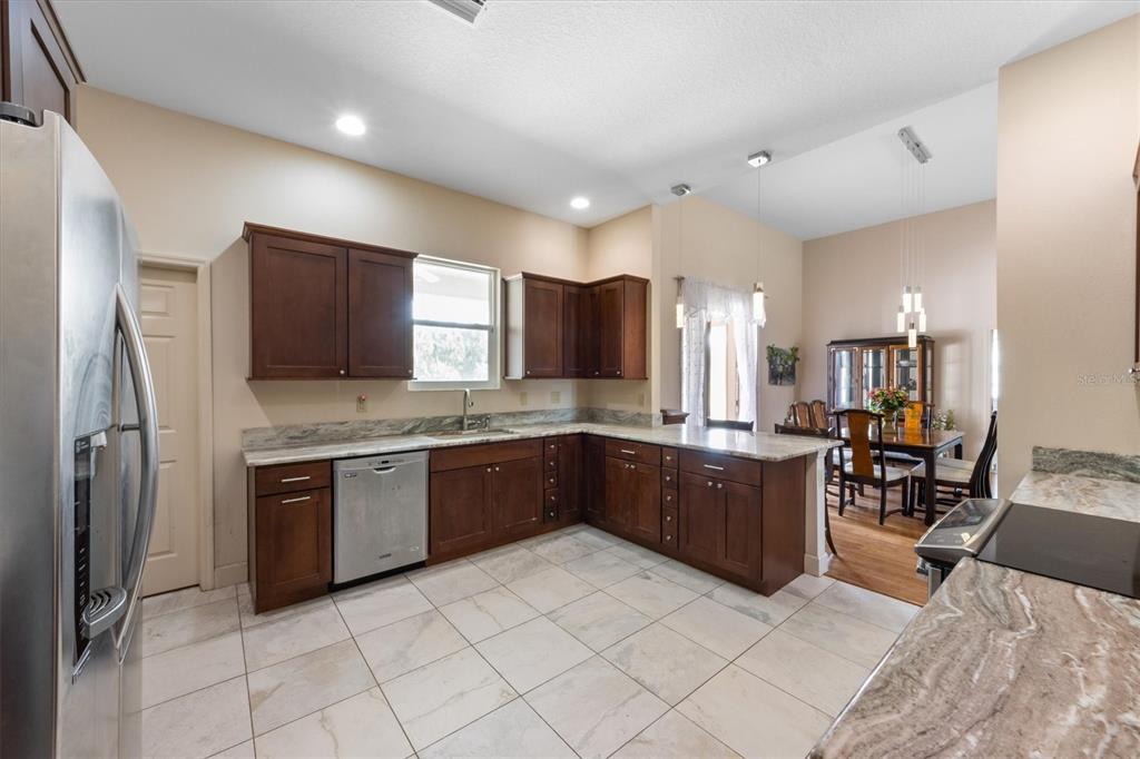 3310 Twin Rivers Trail Parrish, FL 34219 - Photo 7 of 42 a large kitchen with stainless steel appliances kitchen island granite countertop a refrigerator and a stove top oven