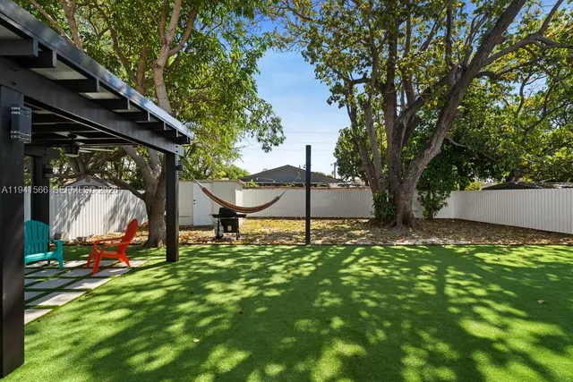 a backyard of a house with table and chairs under an umbrella