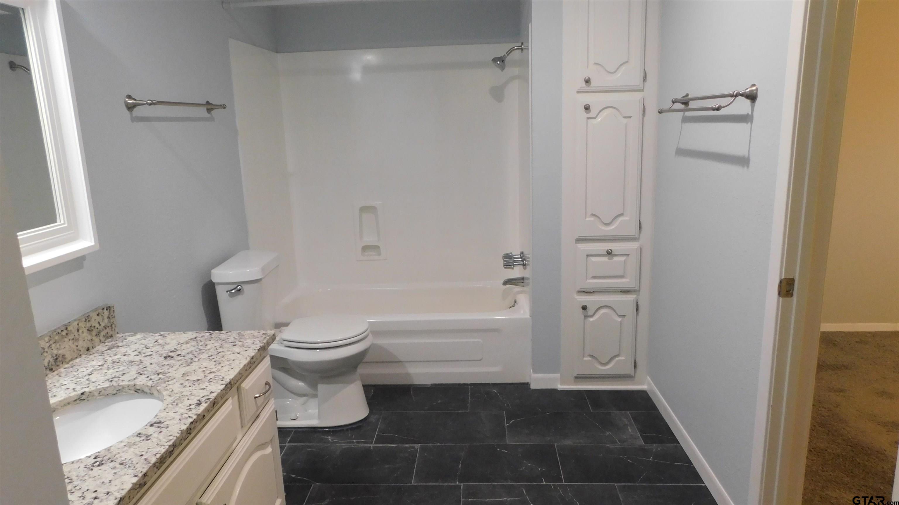 1360 Bridle Path Lane Hideaway, TX 75771 - Photo 13 of 16 a bathroom with a granite countertop sink toilet and shower