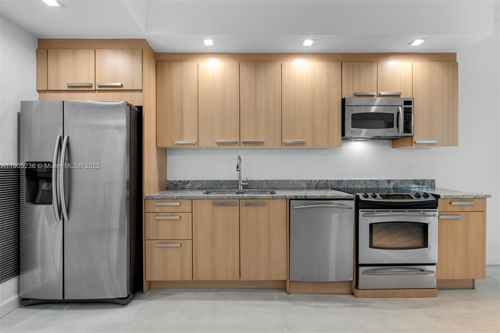 2001 Meridian Avenue, Unit 327 Miami Beach, FL 33139 - Photo 7 of 15 a kitchen with granite countertop stainless steel appliances and wooden cabinets