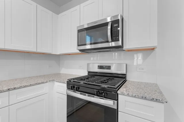 a kitchen with stainless steel appliances granite countertop white cabinets and a stove top oven