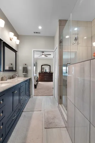 a large bathroom with a glass shower door a sink and a mirror