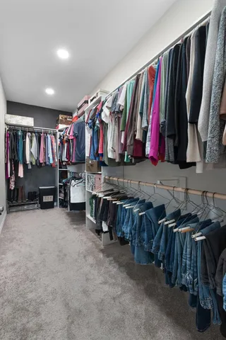 a view of walk in closet with clothes and shoes