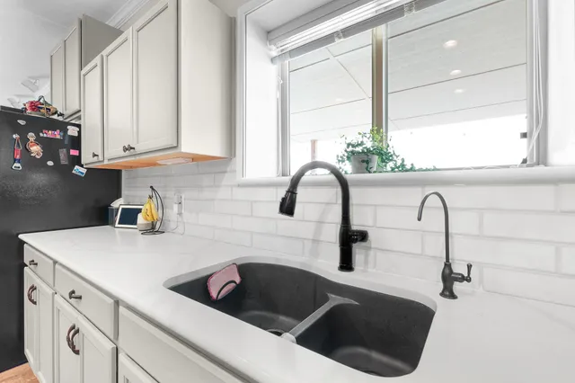 a kitchen with white cabinets a sink and a stove with wooden floor