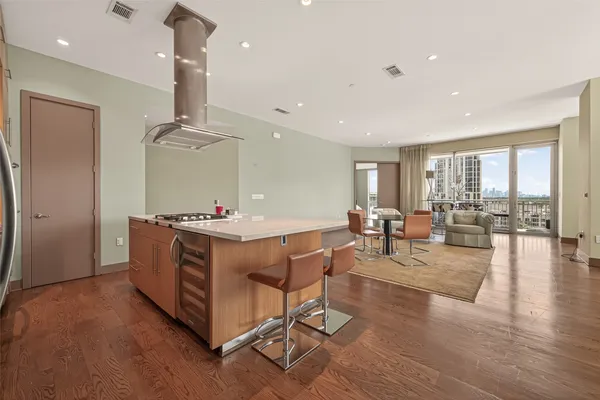 a living room with couches and kitchen view with wooden floor