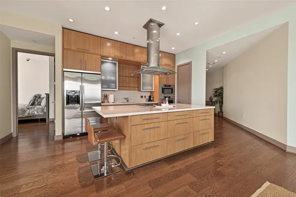 a room with kitchen island stainless steel appliances a couch and a view of living room