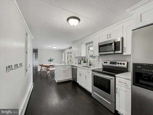 a kitchen with stainless steel appliances a stove a sink cabinets and a refrigerator