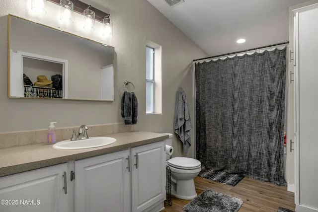 a bathroom with a granite countertop toilet sink and mirror