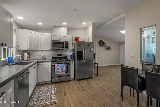 a kitchen with granite countertop a stove top oven a sink dishwasher a dining table and chairs