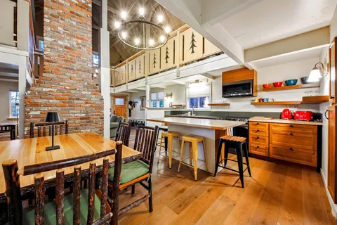 a kitchen with stainless steel appliances kitchen island granite countertop a table chairs in it and wooden floors