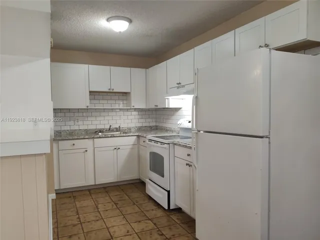 a kitchen with white cabinets and white appliances