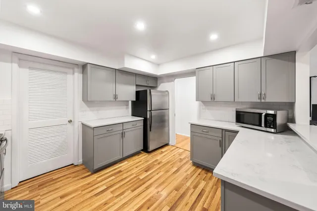 a kitchen with a sink a stove a refrigerator and white cabinets