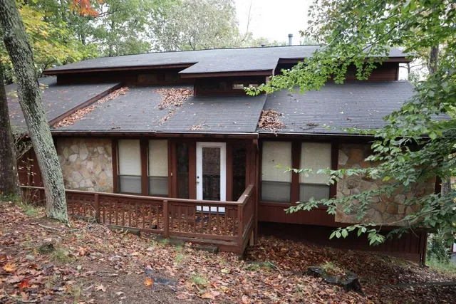 a view of a house with a yard plants and large tree