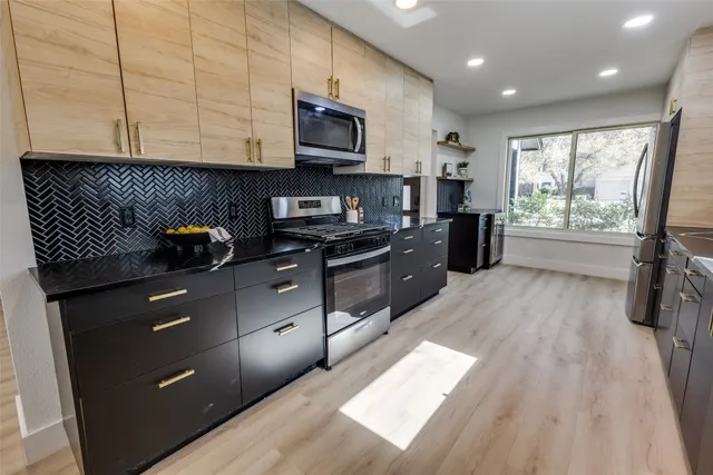 a kitchen with stainless steel appliances granite countertop a stove a sink and a microwave