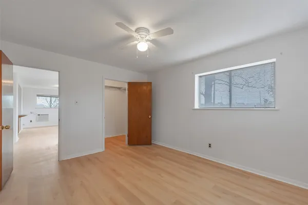 a view of an empty room with wooden floor and a ceiling fan