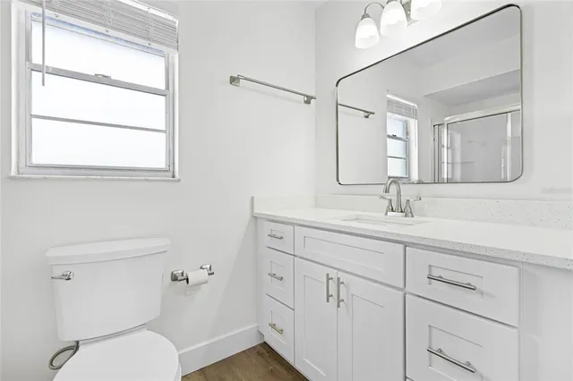 a bathroom with a toilet a sink a mirror and a window