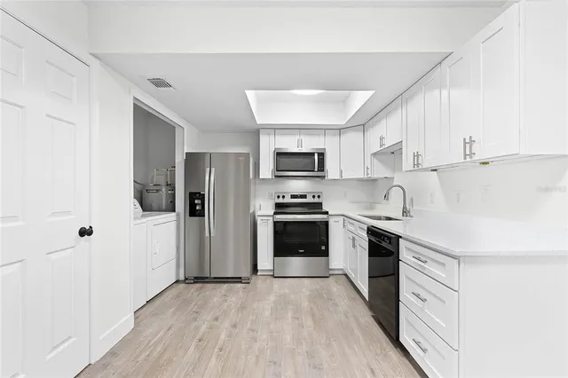 a kitchen with stainless steel appliances a stove a sink dishwasher a refrigerator and a oven with wooden floor