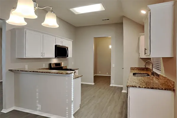 a kitchen with granite countertop a stove top oven a sink a counter space and cabinets