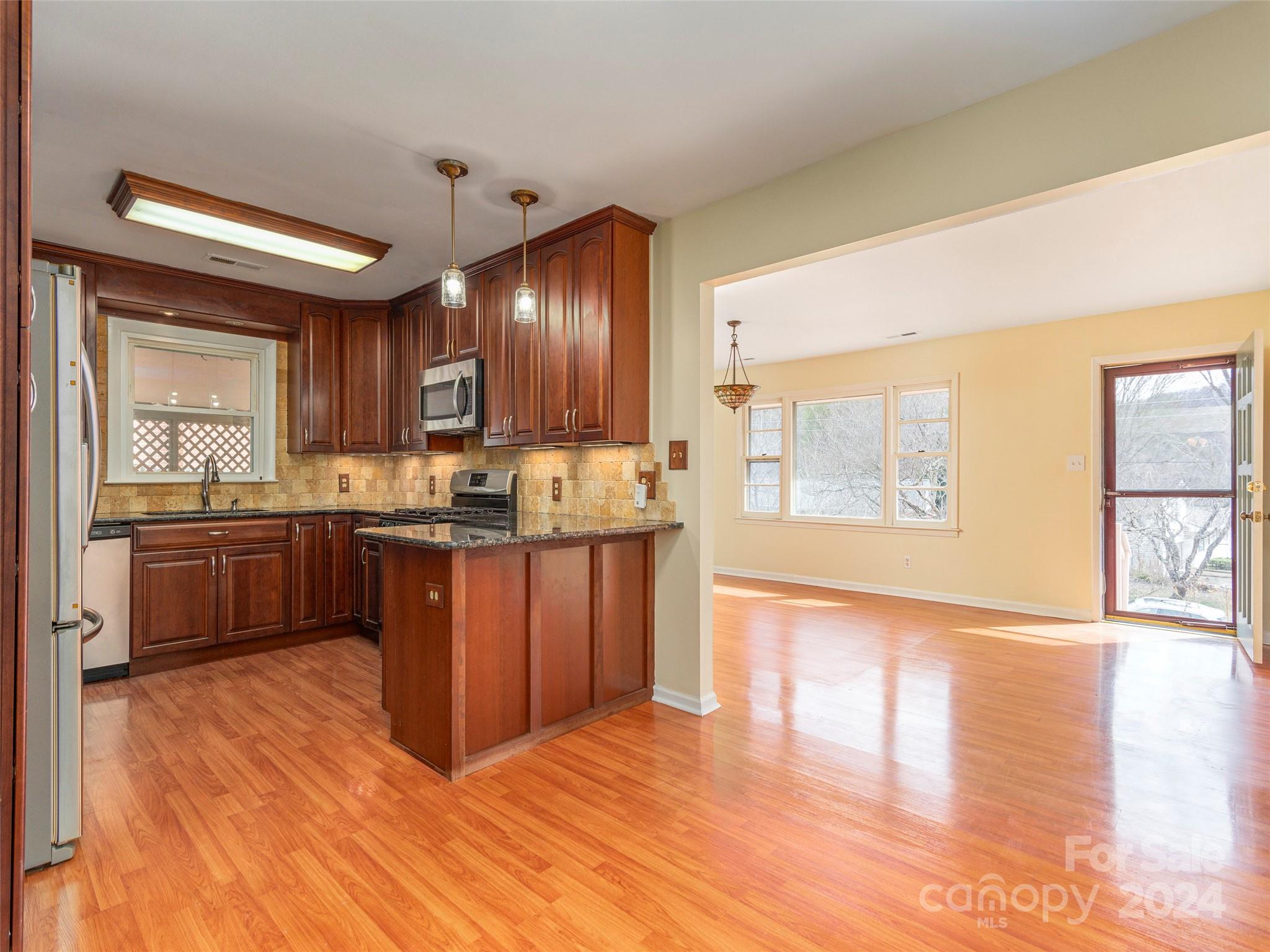 40 Wagon Road Asheville, NC 28805 - Photo 6 of 29 a kitchen with kitchen island granite countertop wooden floors and stainless steel appliances
