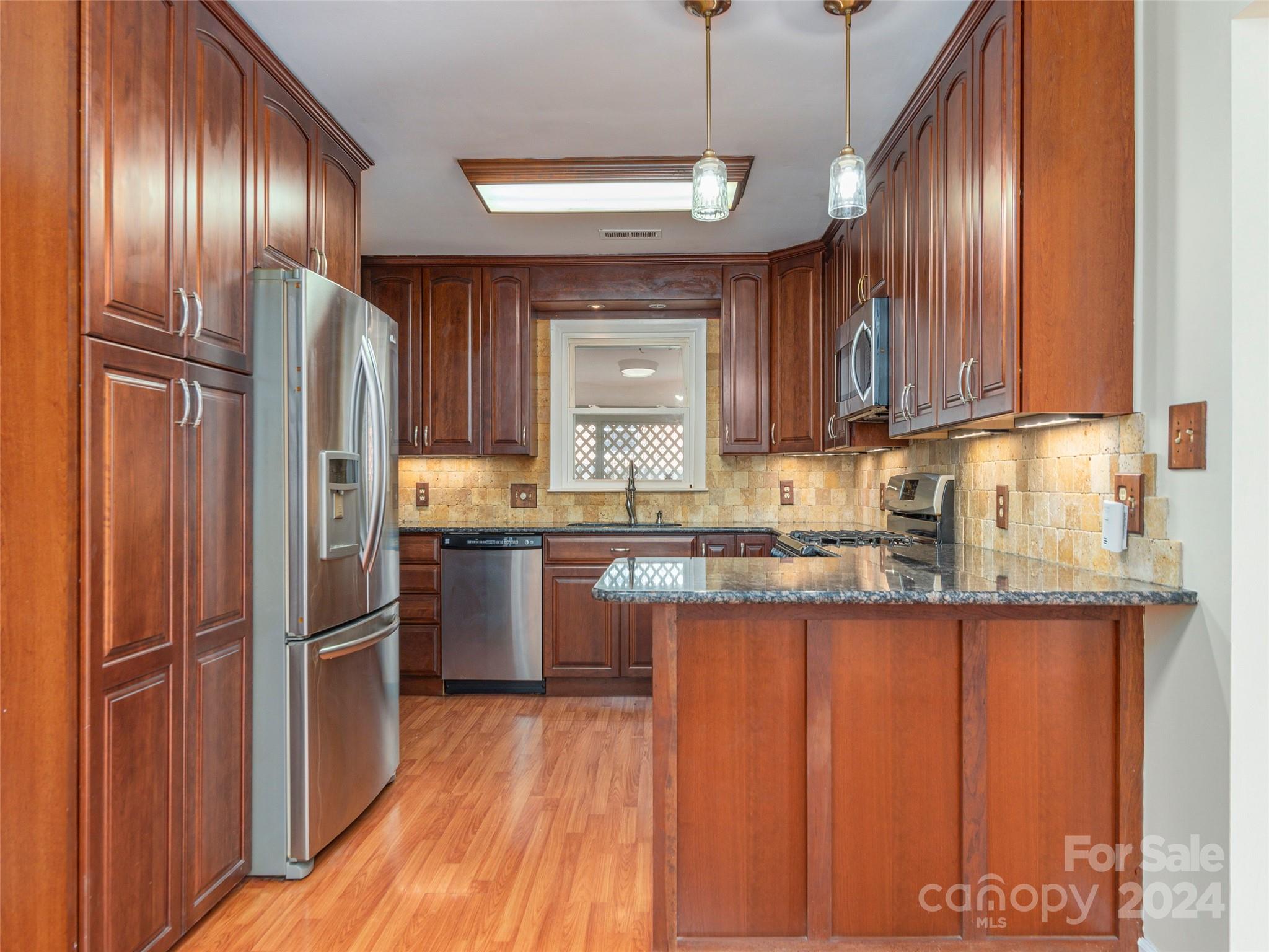 40 Wagon Road Asheville, NC 28805 - Photo 8 of 29 a kitchen with granite countertop wooden cabinets a refrigerator and a sink