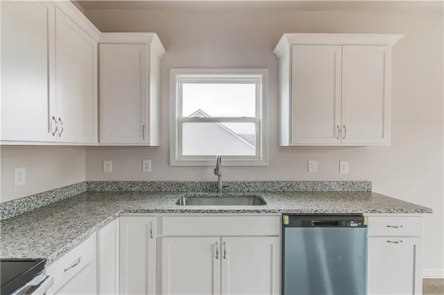 a kitchen with granite countertop white cabinets and a sink