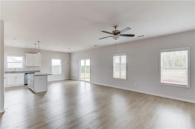 a view of an empty room with a kitchen and wooden floor
