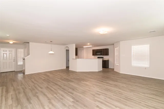 a view of a big room with wooden floor and windows