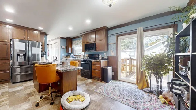 a kitchen with stainless steel appliances granite countertop a refrigerator a stove top oven and a dining table with wooden floor