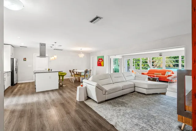 a living room with furniture wooden floor and a kitchen view