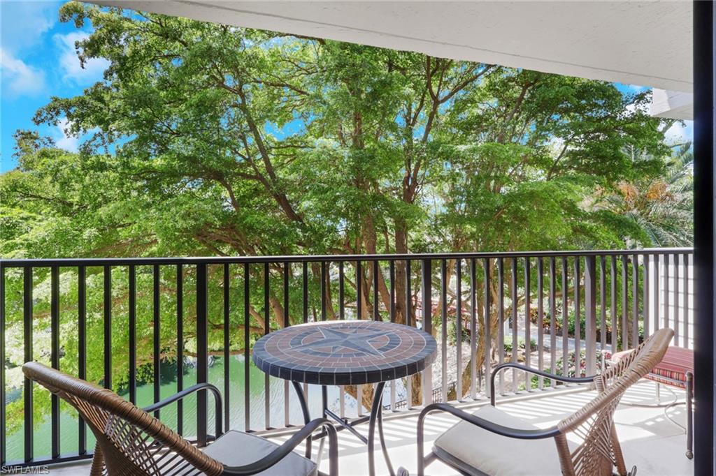 600 Neapolitan Way, Unit 357 Naples, FL 34103 - Photo 14 of 25 a view of a balcony with a wooden floor and outdoor seating
