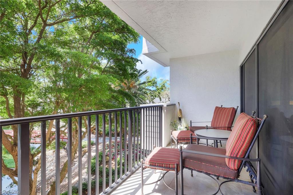 600 Neapolitan Way, Unit 357 Naples, FL 34103 - Photo 24 of 25 a balcony with wooden floor and outdoor seating