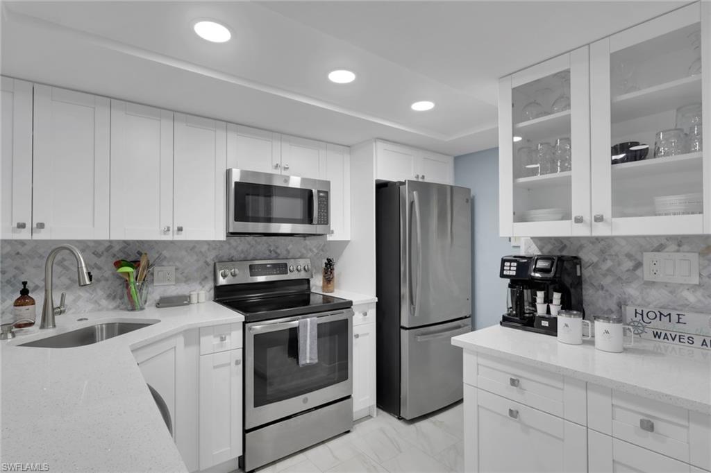 600 Neapolitan Way, Unit 357 Naples, FL 34103 - Photo 3 of 25 a kitchen with a sink stainless steel appliances and cabinets