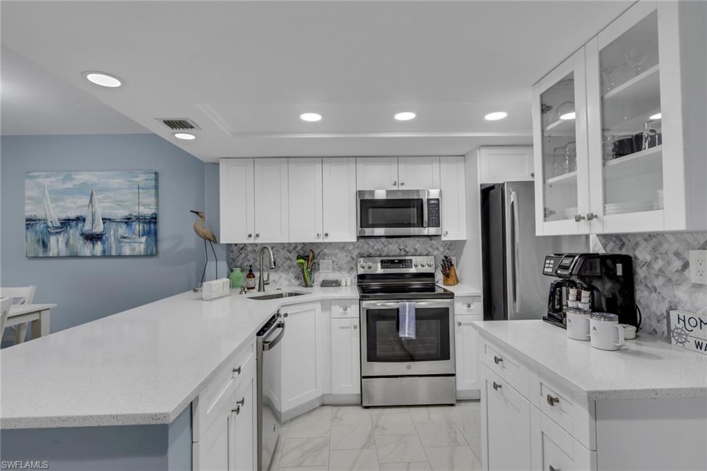 600 Neapolitan Way, Unit 357 Naples, FL 34103 - Photo 4 of 25 a kitchen with stainless steel appliances a stove sink microwave and cabinets