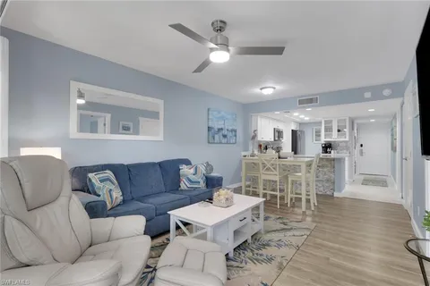 a living room with furniture kitchen view and a wooden floor