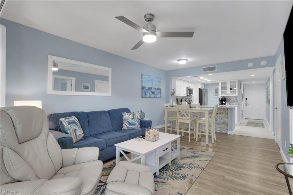 600 Neapolitan Way, Unit 357 Naples, FL 34103 - Photo 7 of 25 a living room with furniture kitchen view and a wooden floor