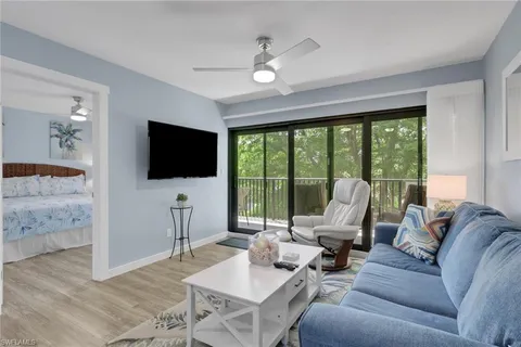 a living room with furniture a flat screen tv and a floor to ceiling window