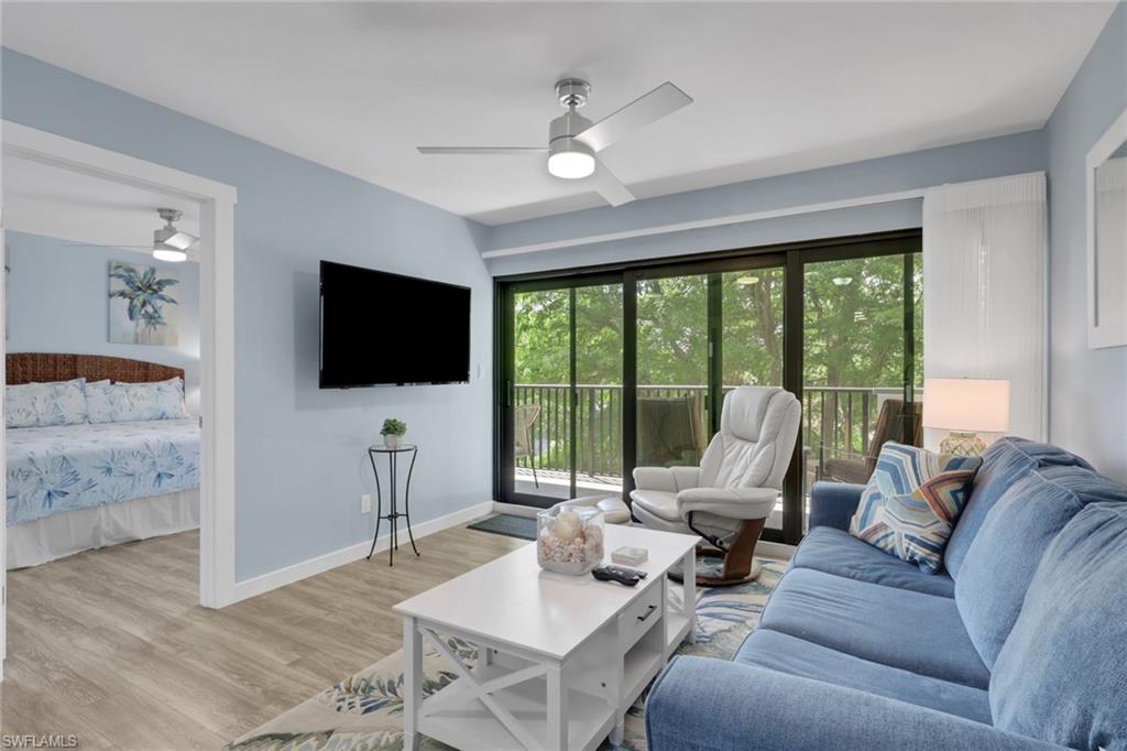 600 Neapolitan Way, Unit 357 Naples, FL 34103 - Photo 10 of 25 a living room with furniture a flat screen tv and a floor to ceiling window