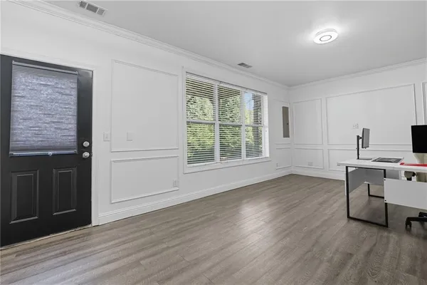 a view of a kitchen and an empty room with wooden floor and a window