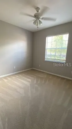 an empty room with a window and a ceiling fan