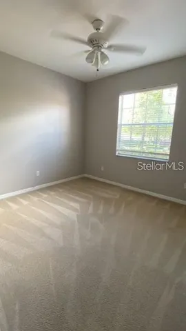 an empty room with a window and a ceiling fan