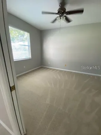 an empty room with windows and fan
