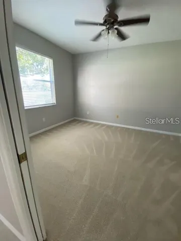 an empty room with windows and fan