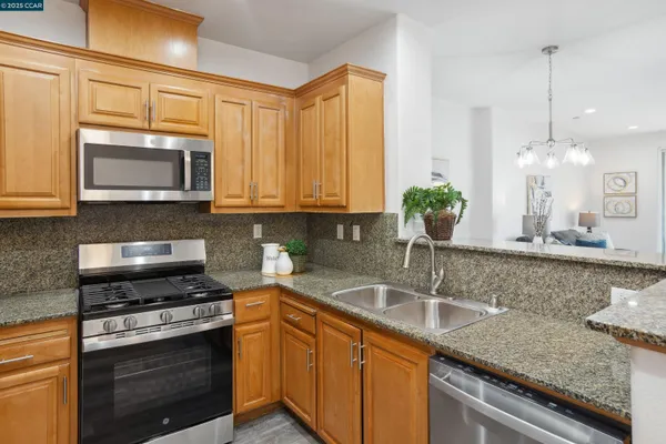 a kitchen with granite countertop a sink stainless steel appliances and cabinets
