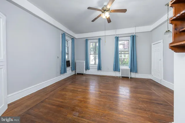a view of an empty room with window and wooden floor