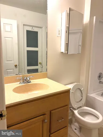 a bathroom with a granite countertop toilet sink and mirror