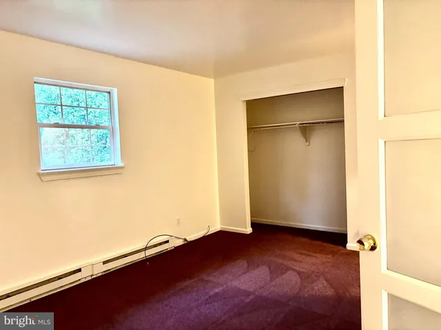 an empty room with wooden floor closet and windows